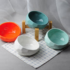 Three ceramic bowls in orange, white and teal on a mat