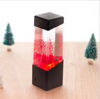Lamp glowing red beside small model fir trees