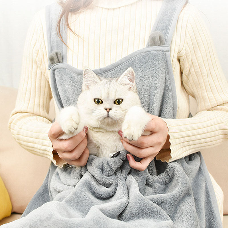 Person holding a white cat in the apron with both hands