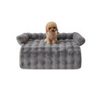 Poodle sitting on the grey mat with its bolster edge