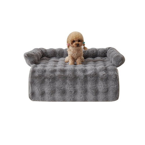 Poodle sitting on the grey mat with its bolster edge